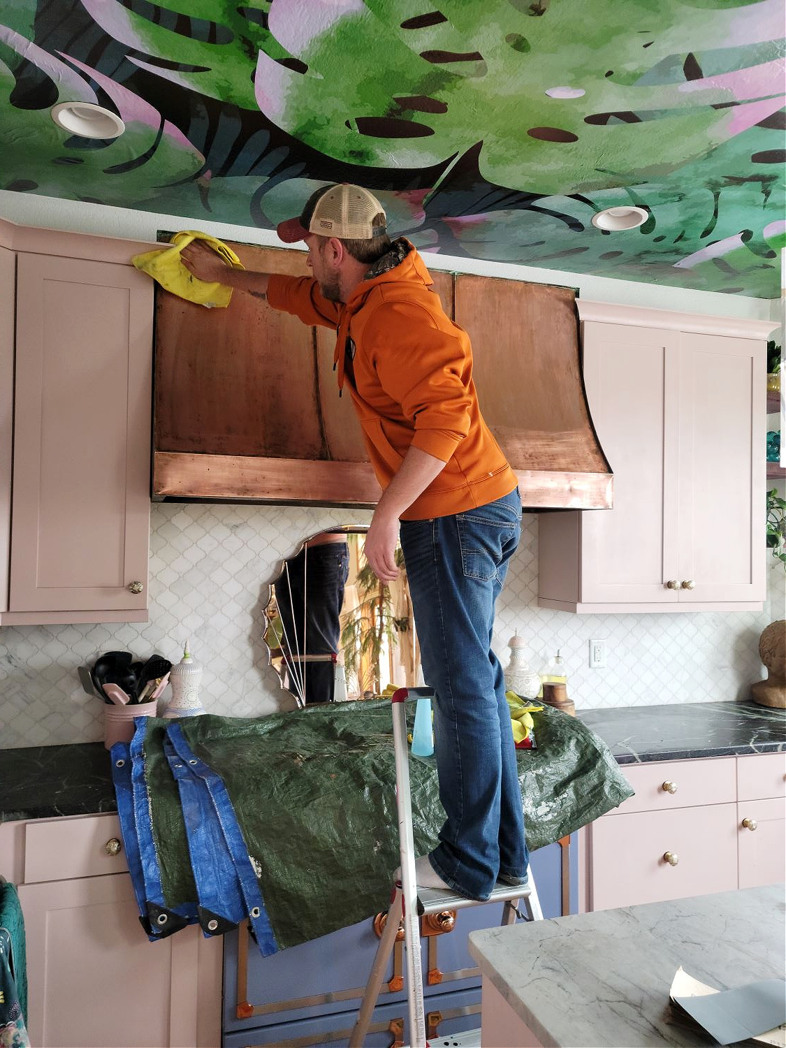 Copper Hood by popular CO home design blog, Eclectic Twis: image of a man standing on foot ladder and cleaning a copper hood