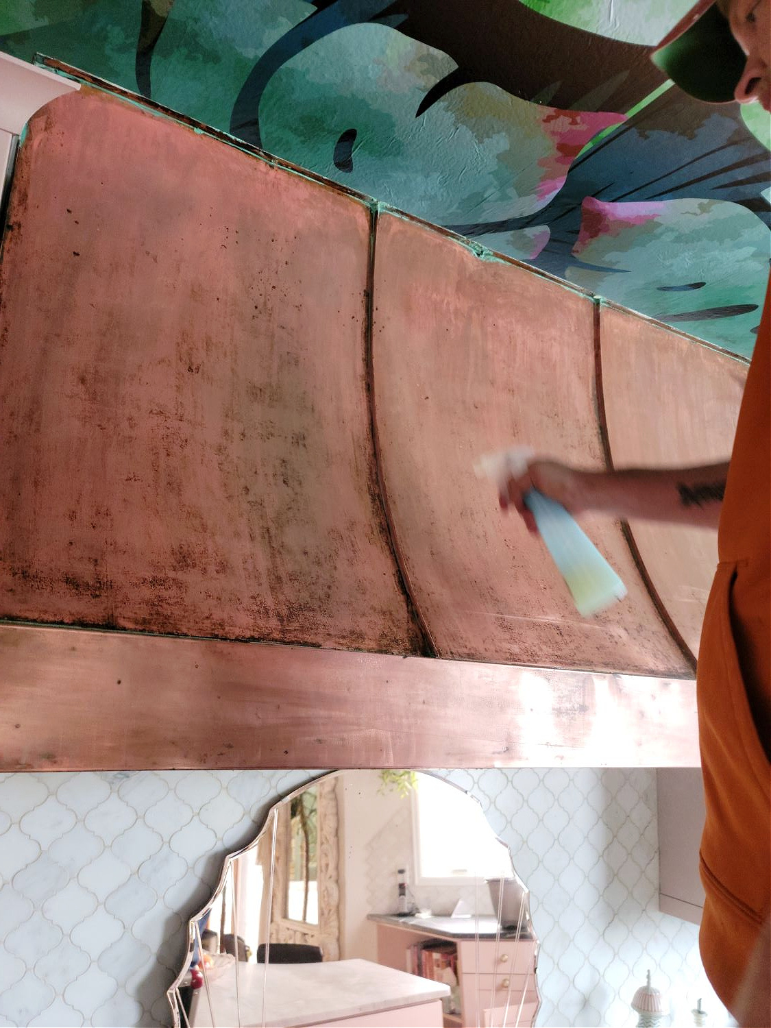 Copper Hood by popular CO home design blog, Eclectic Twist: image of a man spraying a cleaning solution on a copper hood. 