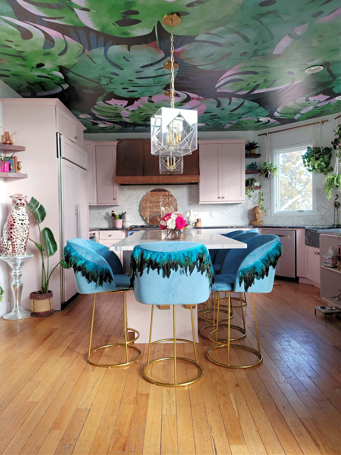 DIY Counter Stools by popular Colorado home design blog, Eclectic Twist: image of blue fabric counter stools with feather trim detailing in a kitchen with pink cabinets and a botanical wallpapered ceiling.