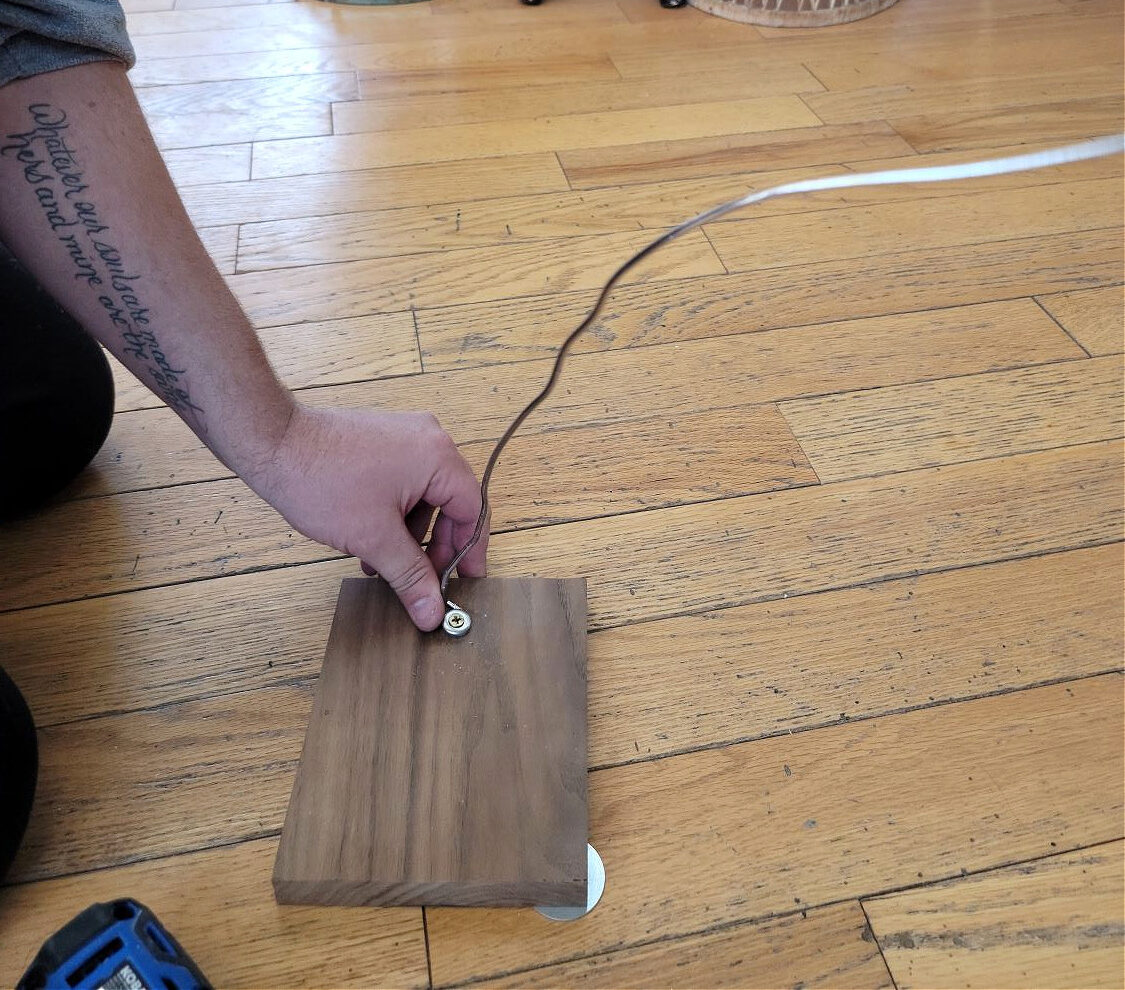 Thrift Store Find by popular CO home design blog, Eclectic Twist: image of a man screwing a wire onto a wooden board.