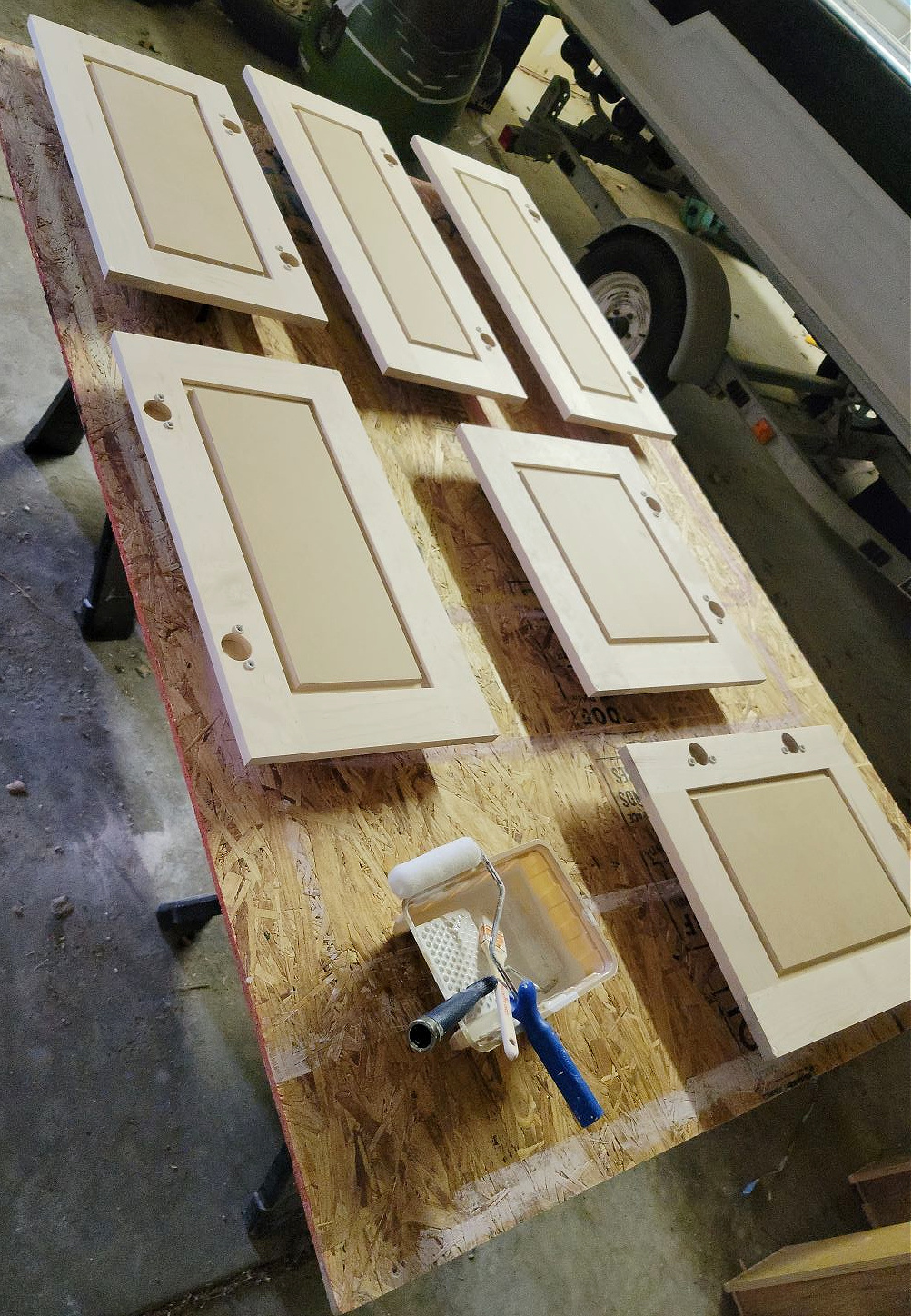 Mixing Your Own Paint Color by popular CO Home Design blog, Eclectic Twist: image of unfinished cabinet doors resting on a plywood table next to a paint pan with a rolling paint brush. 
