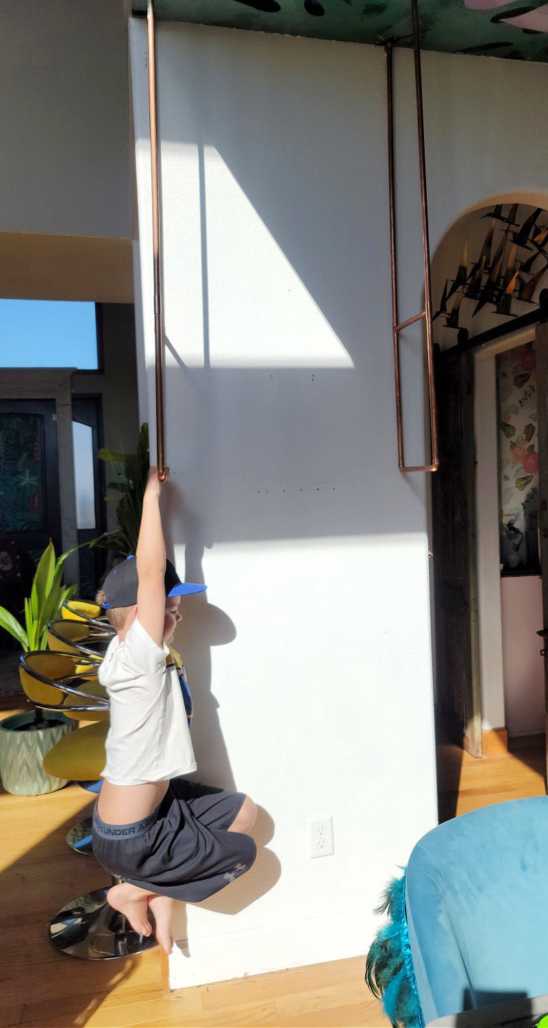 DIY Open Shelving by popular CO home design blog, Eclectic Twist: image of a boy hanging from some mounted copper bars. 