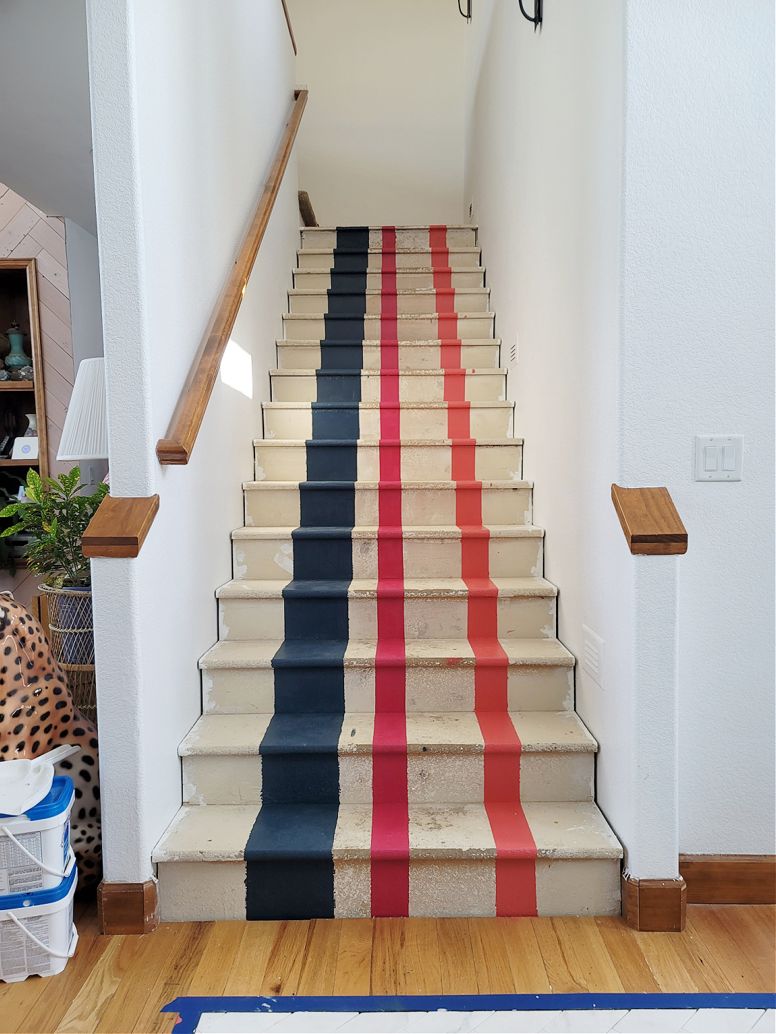 Staircase Makeover by popular CO home design blog, Eclectic Twist: image of a wooden staircase with navy blue, pink and orange stripes painted on it. 