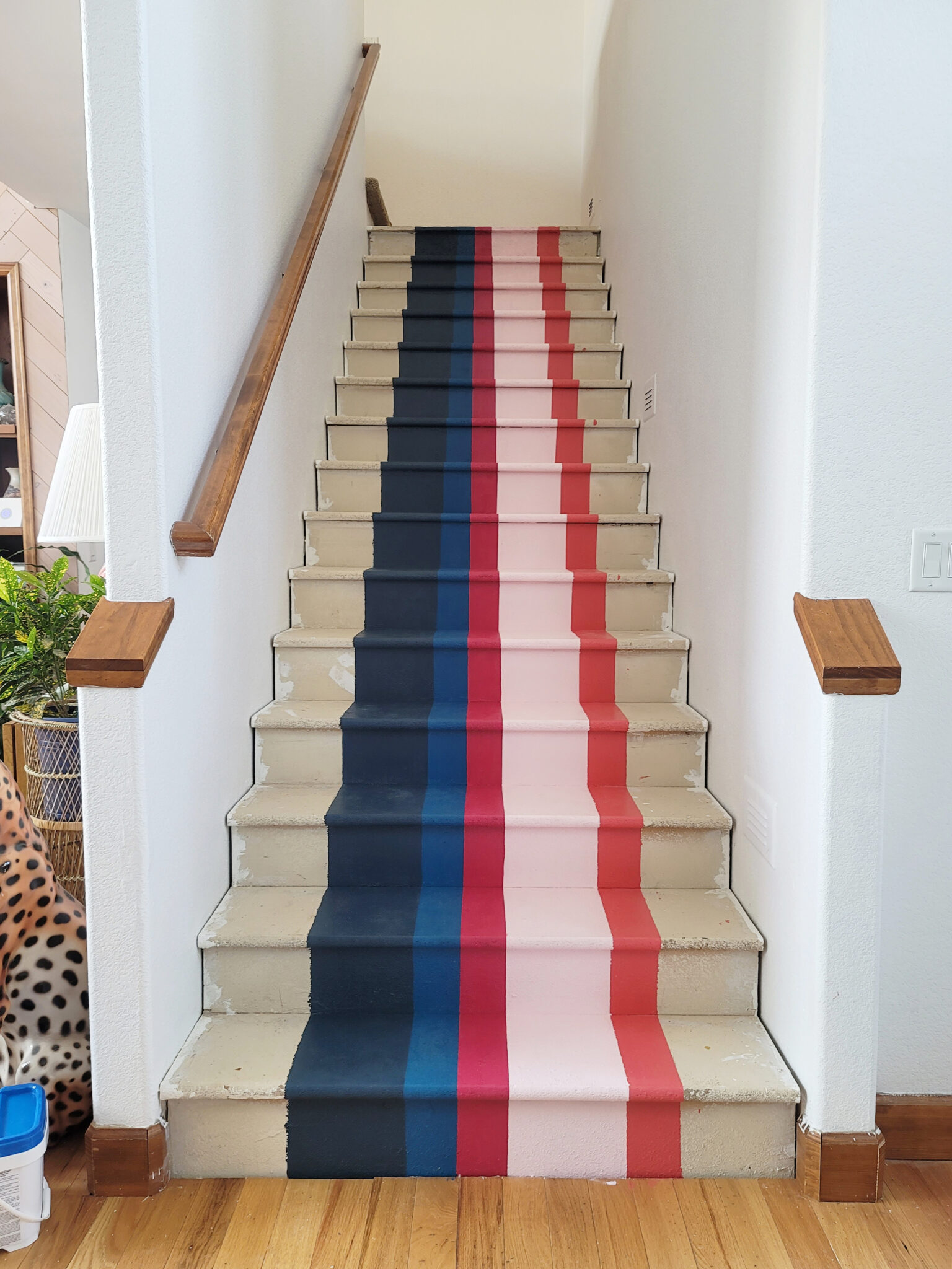 Staircase Makeover by popular CO home design blog, Eclectic Twist: image of navy blue, coral blue, dark pink, light pink and orange stripes painted on it. 